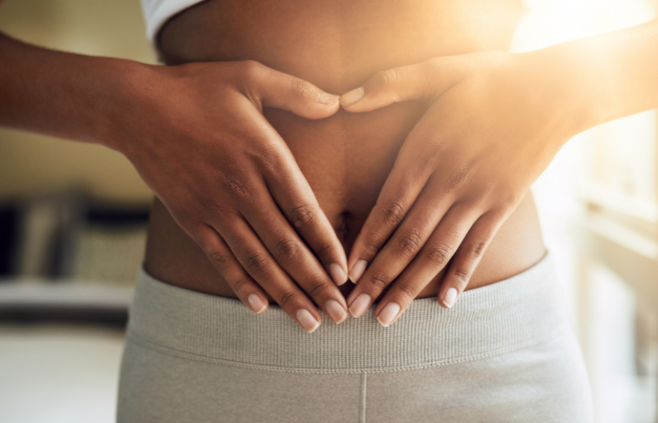 Woman's torso with hands forming a heart over lower abdomen