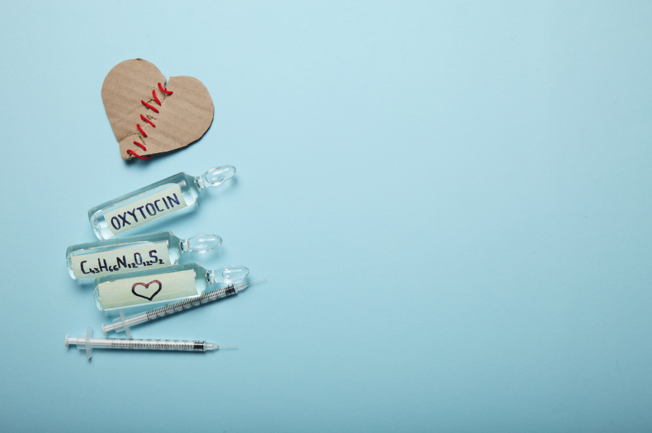 Two syringes and three glass vials labelled with hormones plus a mended broken cardboard heart. 