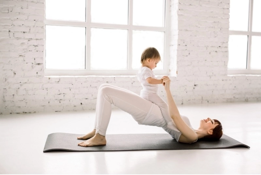Young woman exercising with a baby to illustrating the importance of exercise for pregnancy as well as postpartum.   