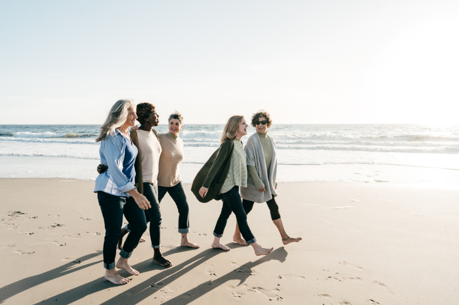 Women walking together on a beach for movement and community to control perimenopause hormones. 