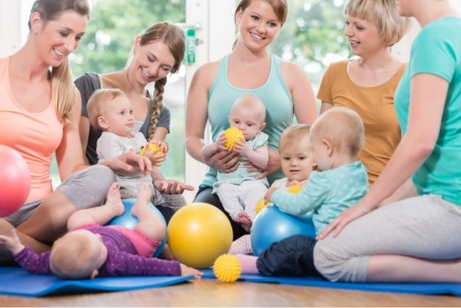 Five young women exercising with their babies shows that returning to exercise postpartum should start easy and build up slowly.