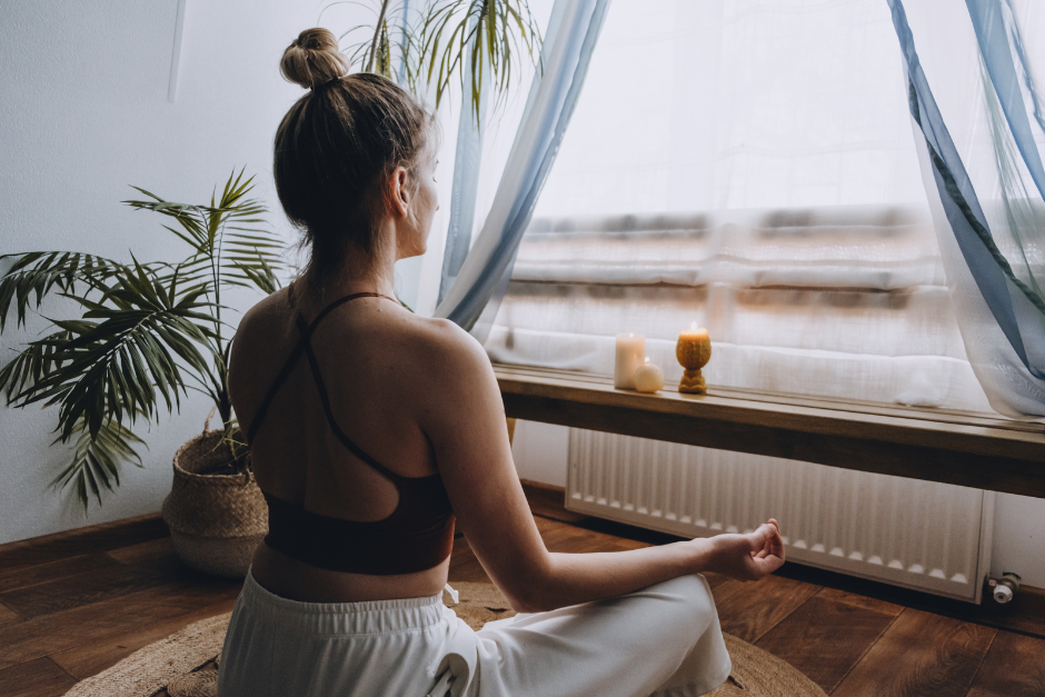 A young woman practicing mindfulness in front of a curtained window