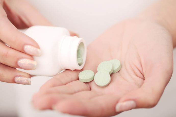 A woman with a bottle of tablets, illustrating antibiotics as treatment for many common vaginal infections.