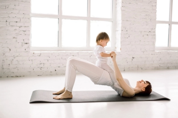 Young woman exercising with a baby to illustrate the importance of exercise for pregnancy as well as postpartum.