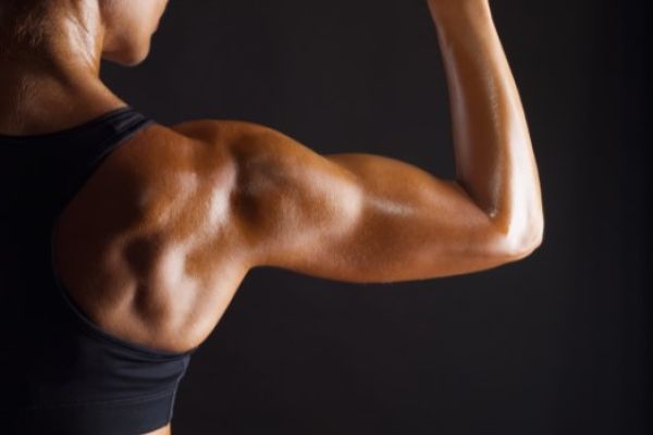 Young woman holding a dumb bell and flexing muscles.